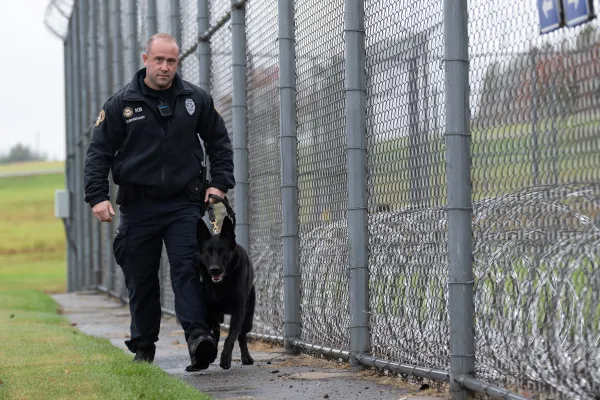 Corrections Officer Jared Surprenant guards the perimeter of a facility with a K9.