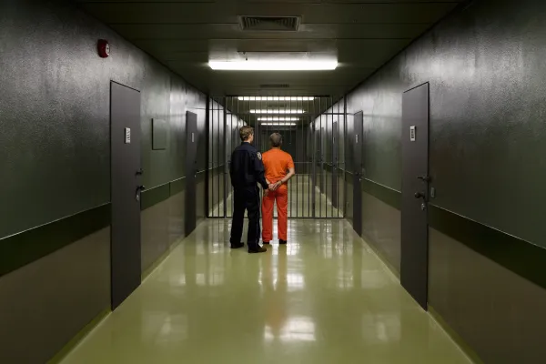 Stock image of a corrections officer leading an inmate down a corridor. Photo credit: Getty.