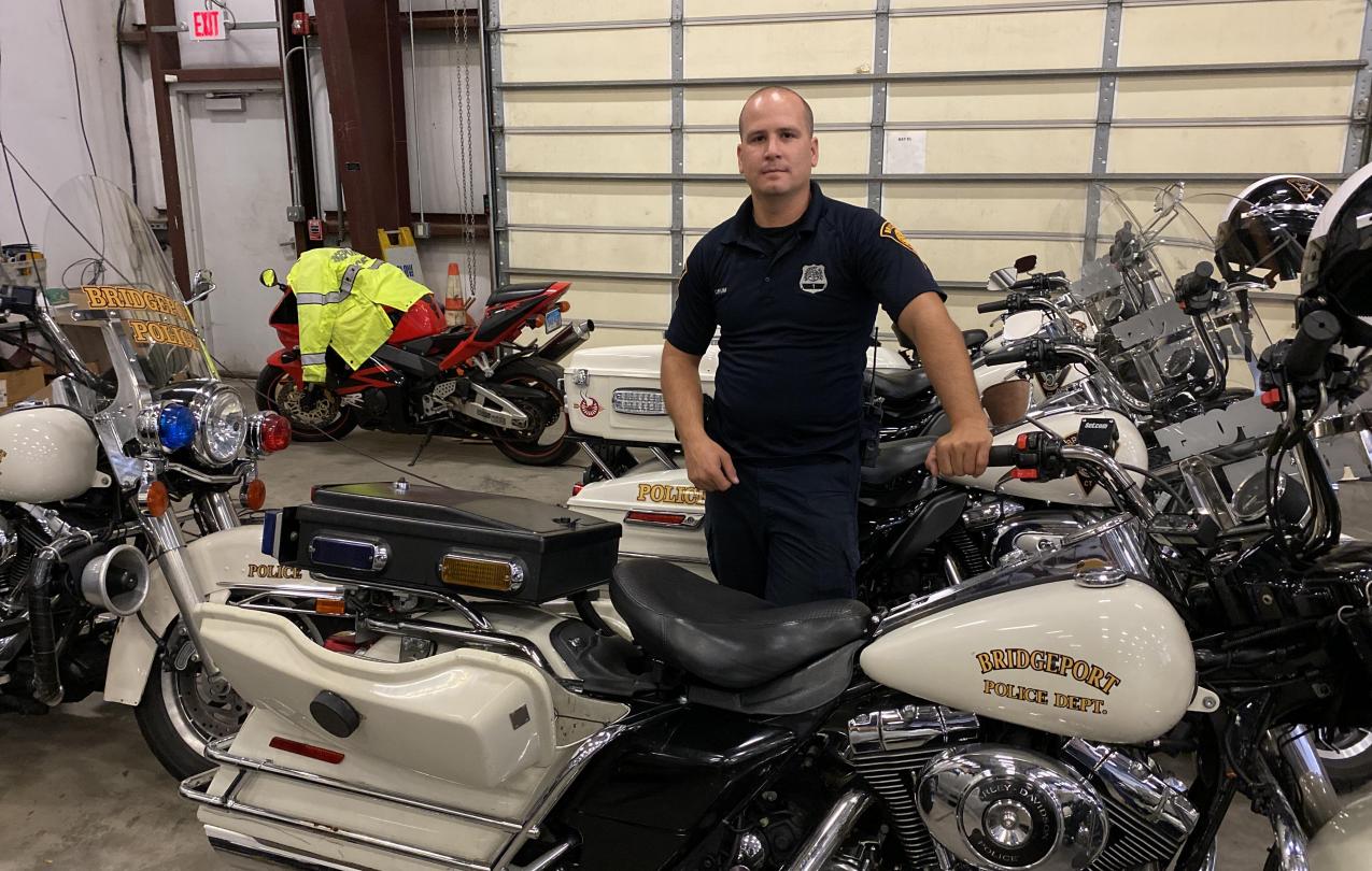Orum standing next to a motorcycle at the Bridgeport Police Department Traffic Division garage. Photo credit: Aaron Gallant/AFSCME.